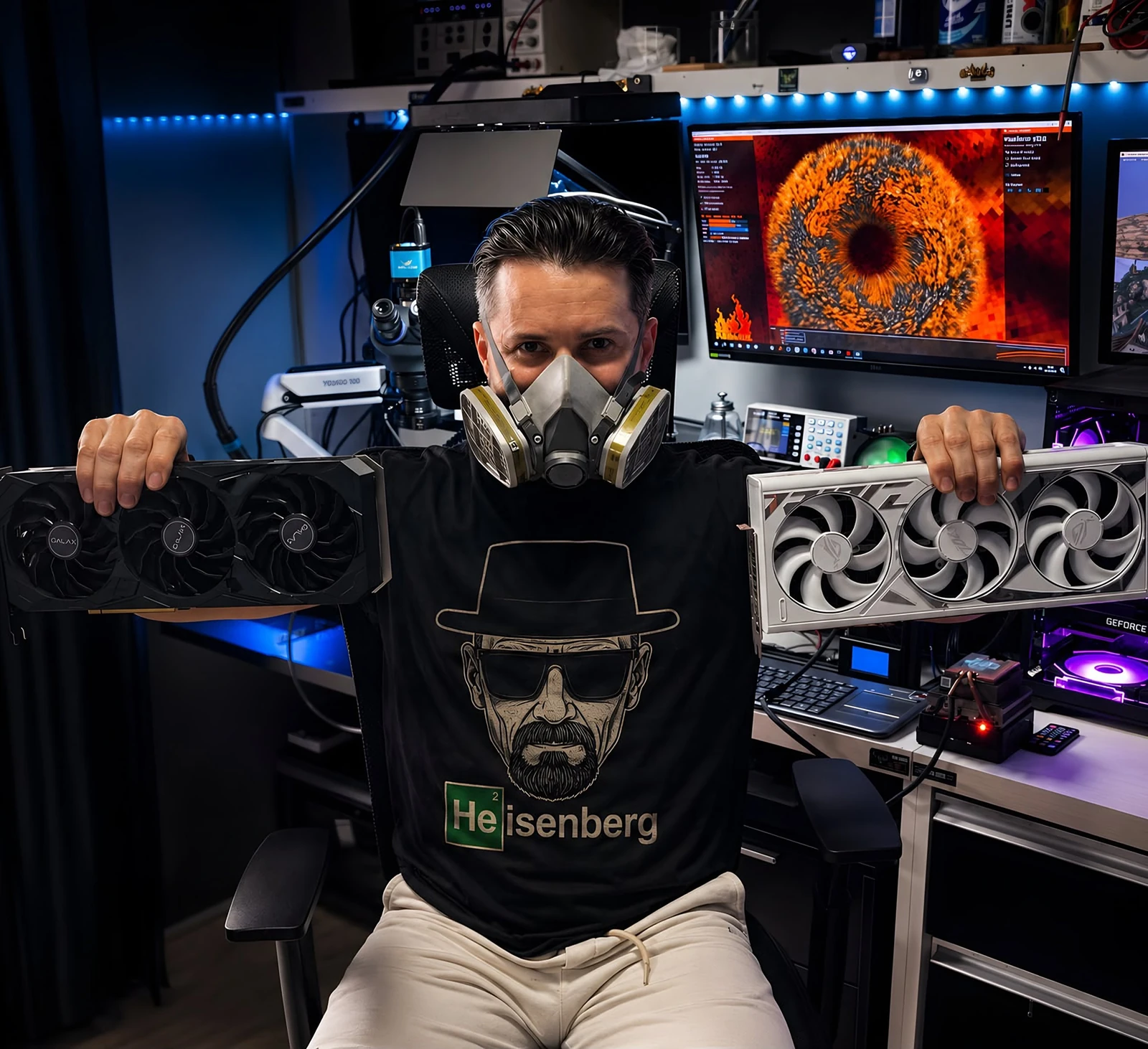 Daniel Rocha no laboratório Dani Hardware segurando duas placas de vídeo, com microscópio e teste de estresse no monitor ao fundo